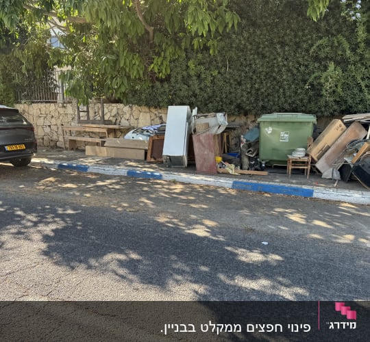 ערימת רהיטים ופסולת ליד פח ירוק ברחוב